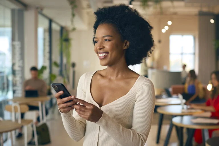 Mulher negra sorrindo mexendo no celular